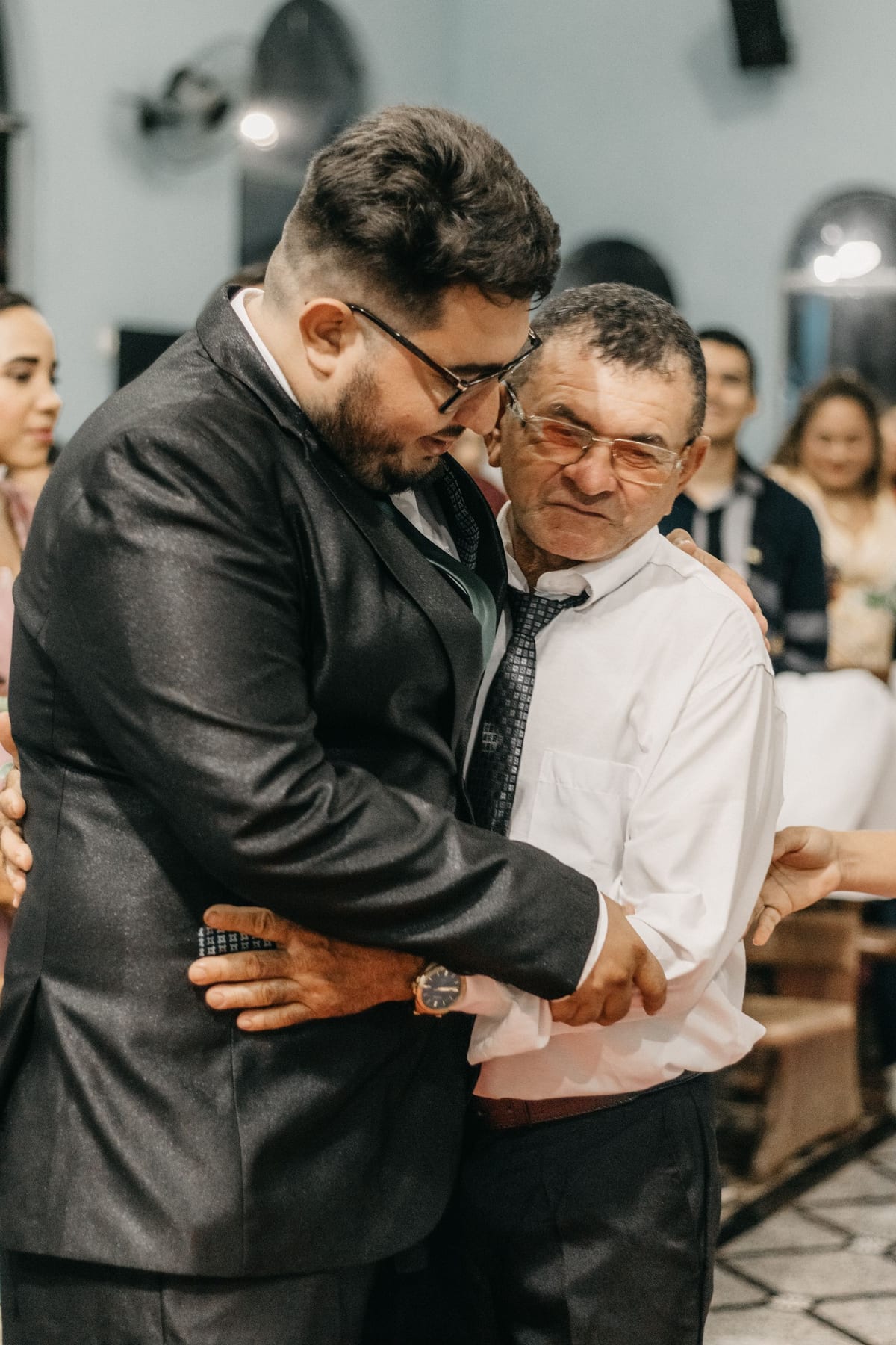 Pai e filho adulto se abraçando em uma festa de família